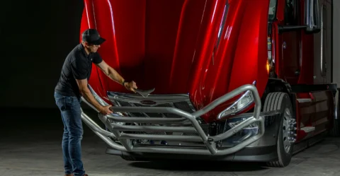 Driver raising a semi-truck grille guard with Xero-G lift assist