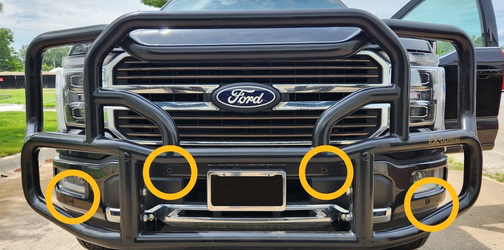 Front bumper of a Ford pickup with an Ex-Guard grille guard, four parking sensor locations circled
