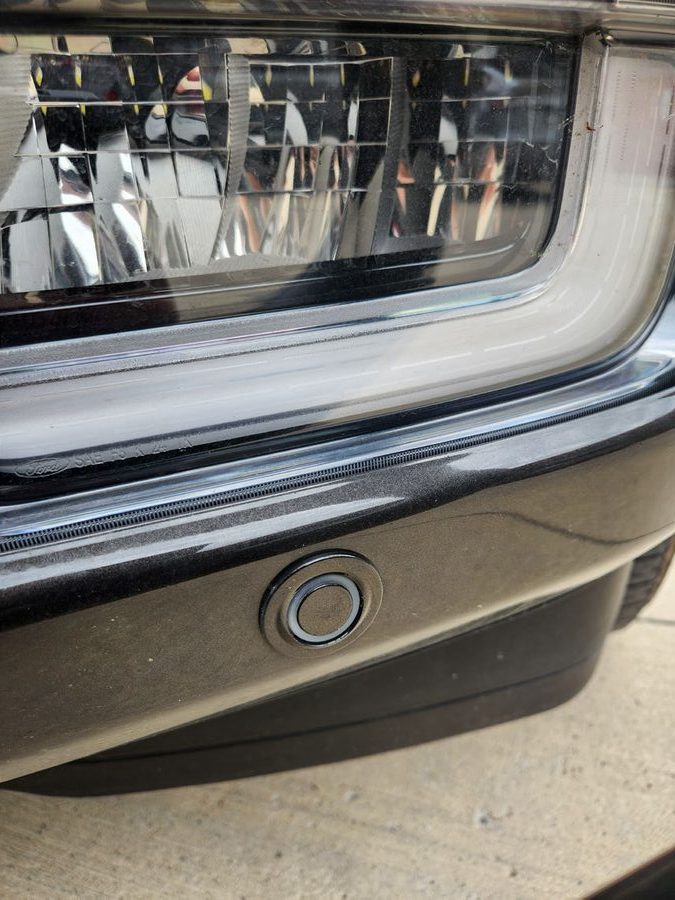 Close-up of a bare front bumper parking sensor before a mute is applied